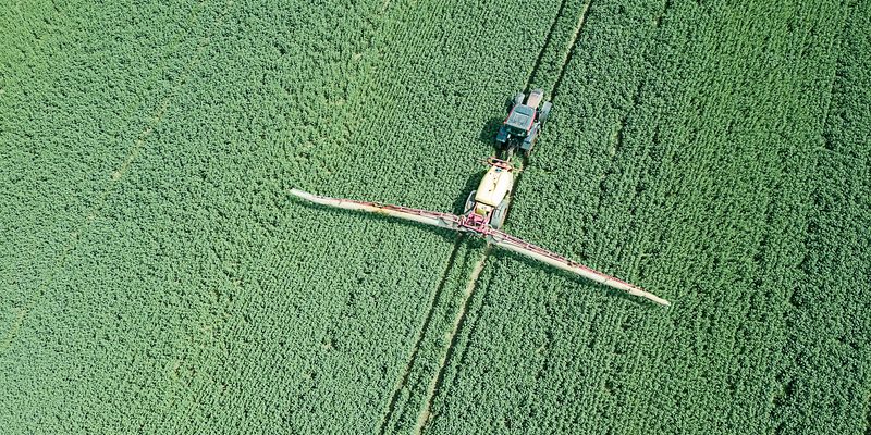 Aerial view Farm machinery spraying chemicals on the large green Aerial view Farm machinery spraying chemicals on a large green field