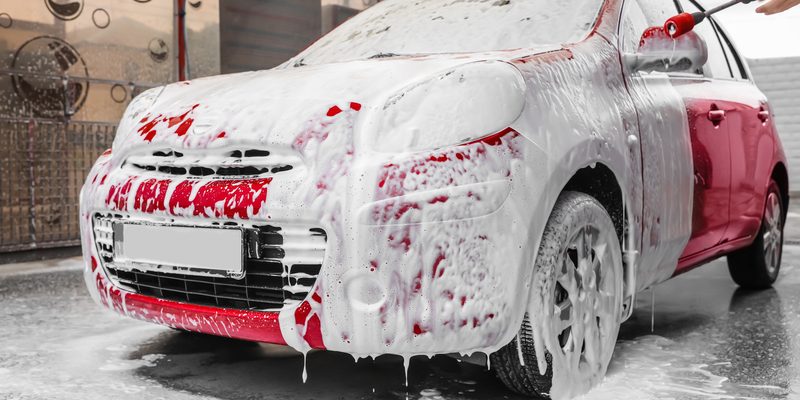 Foaming red auto at car wash. Cleaning service Foaming red auto at car wash