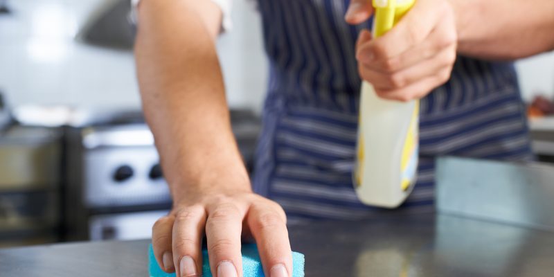 Close Up Of Worker In Restaurant Kitchen Cleaning Down After Ser Close Up Of Worker In Restaurant Kitchen cleaning down a surface